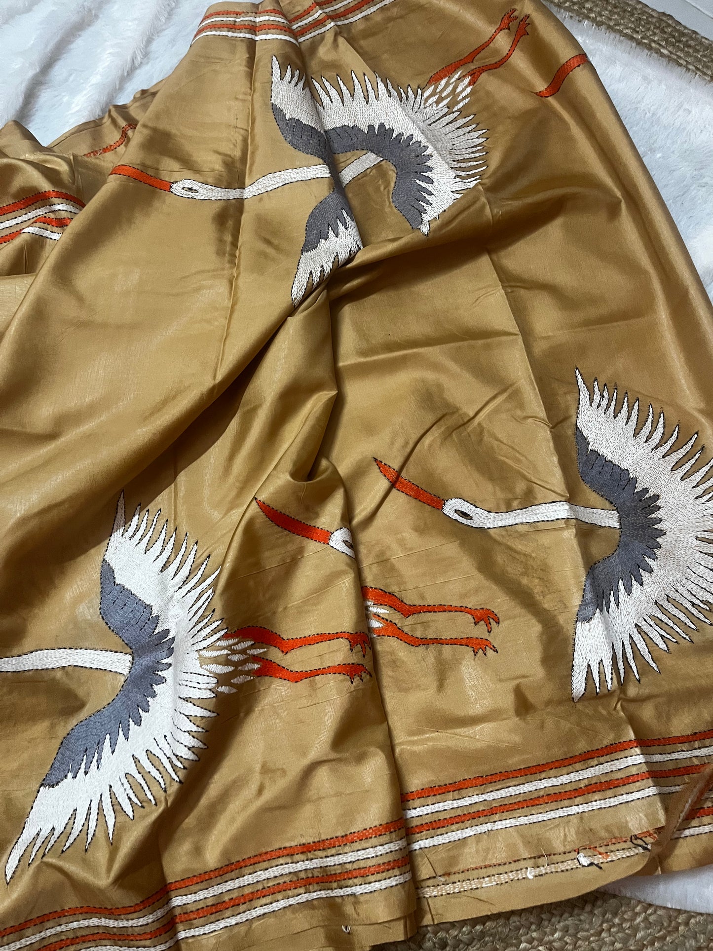 Close-up of handcrafted kantha stitch crane embroidery on beige handwoven silk fabric