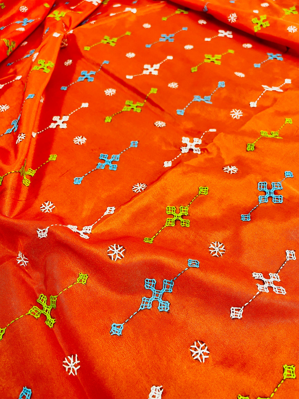 Close-up of orange Bangalore silk saree fabric showing Gujarati stitch motifs