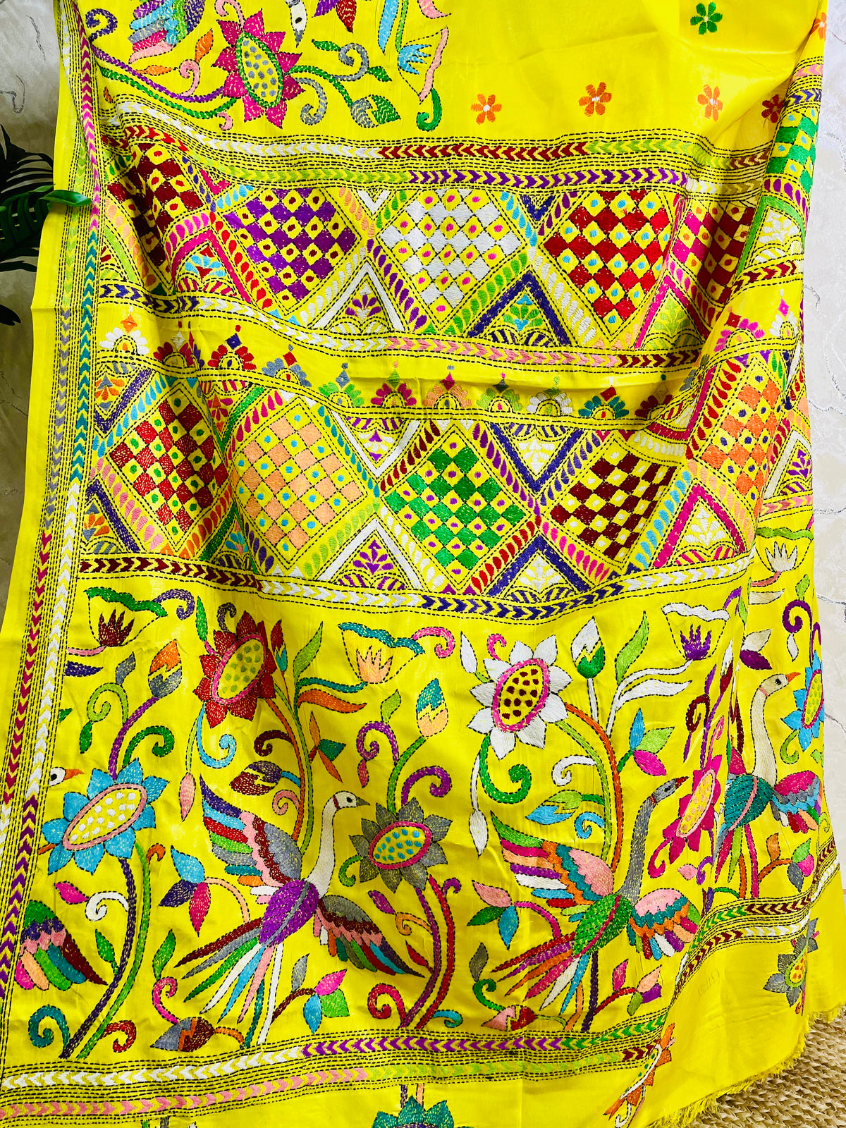 Detailed close-up of the exquisite Nakshi Katha embroidery, highlighting the vivid multi-colored geometric patterns, alongside the large bird and blooming floral motifs