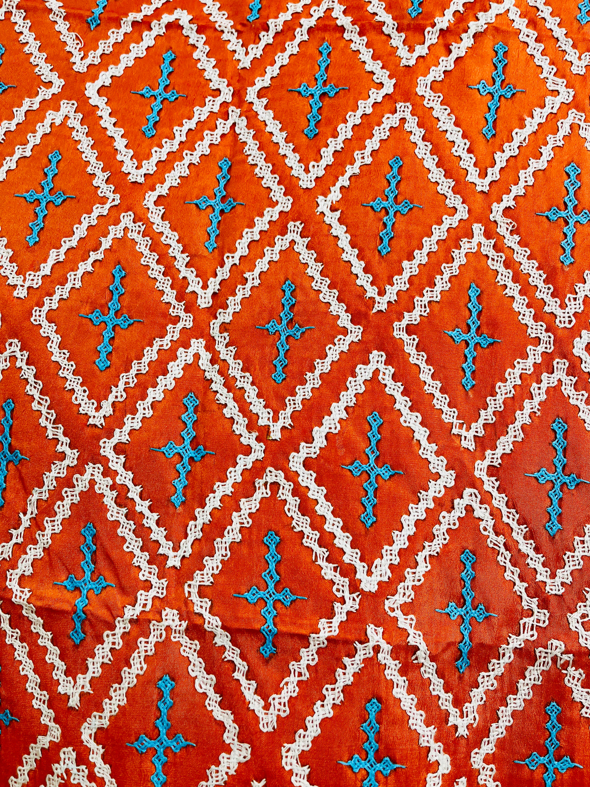 Close-up of orange saree showing kairi paisley border with Kutch cross-stitch