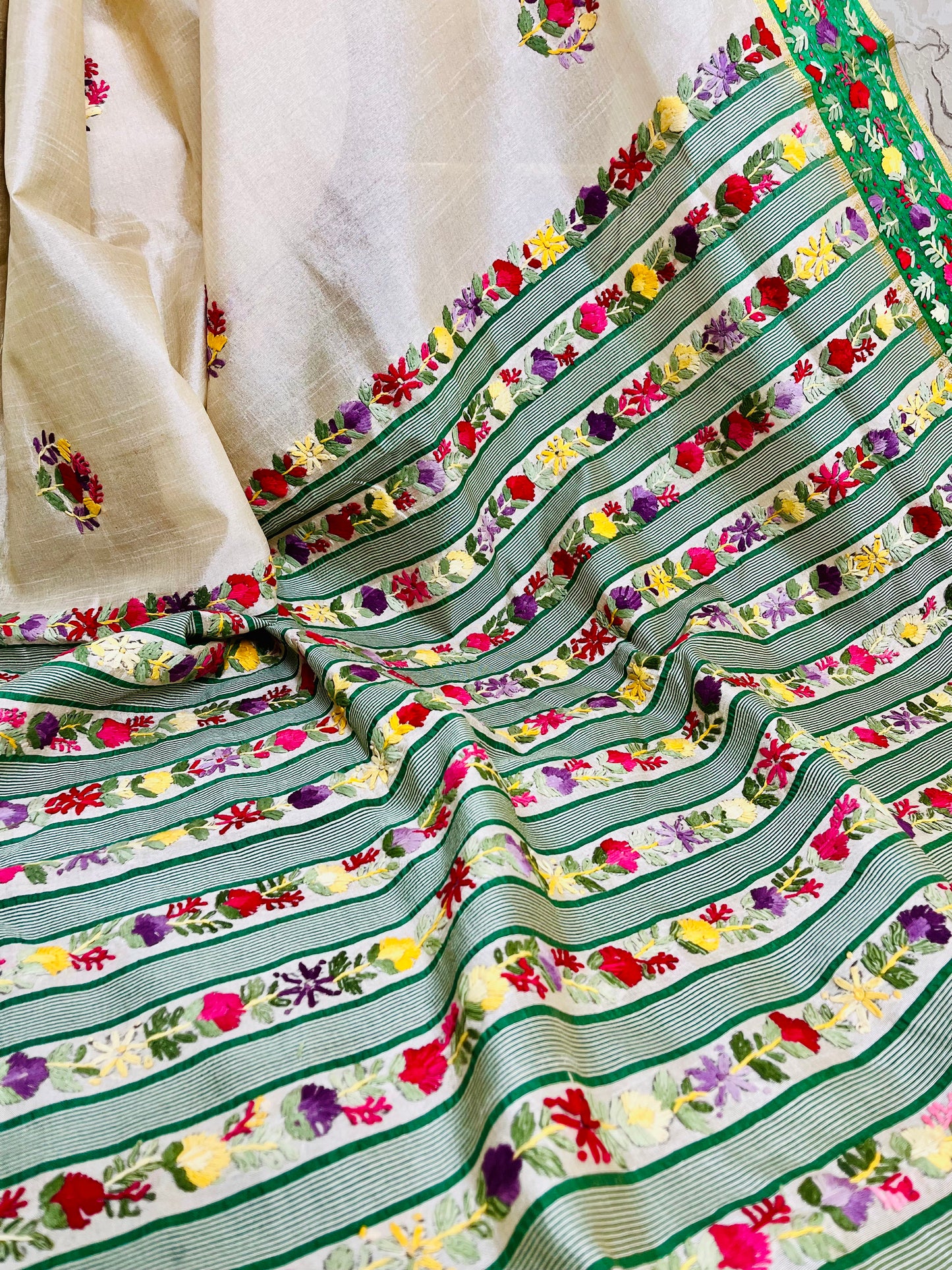 Close-up of Parsi Gara hand-embroidered horizontal floral garden stripes with green woven stripes and Kardana gold detailing on Semi Muga Silk pallu — Desi Aadat