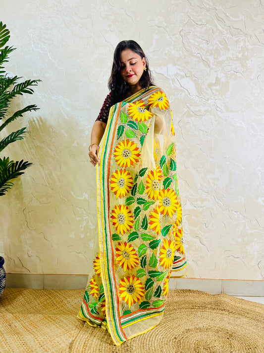 Sunflower Kantha stitch pastel yellow organza saree with all-over hand-embroidered sunflower blooms and multicolour stripe border — side standing view, Desi Aadat