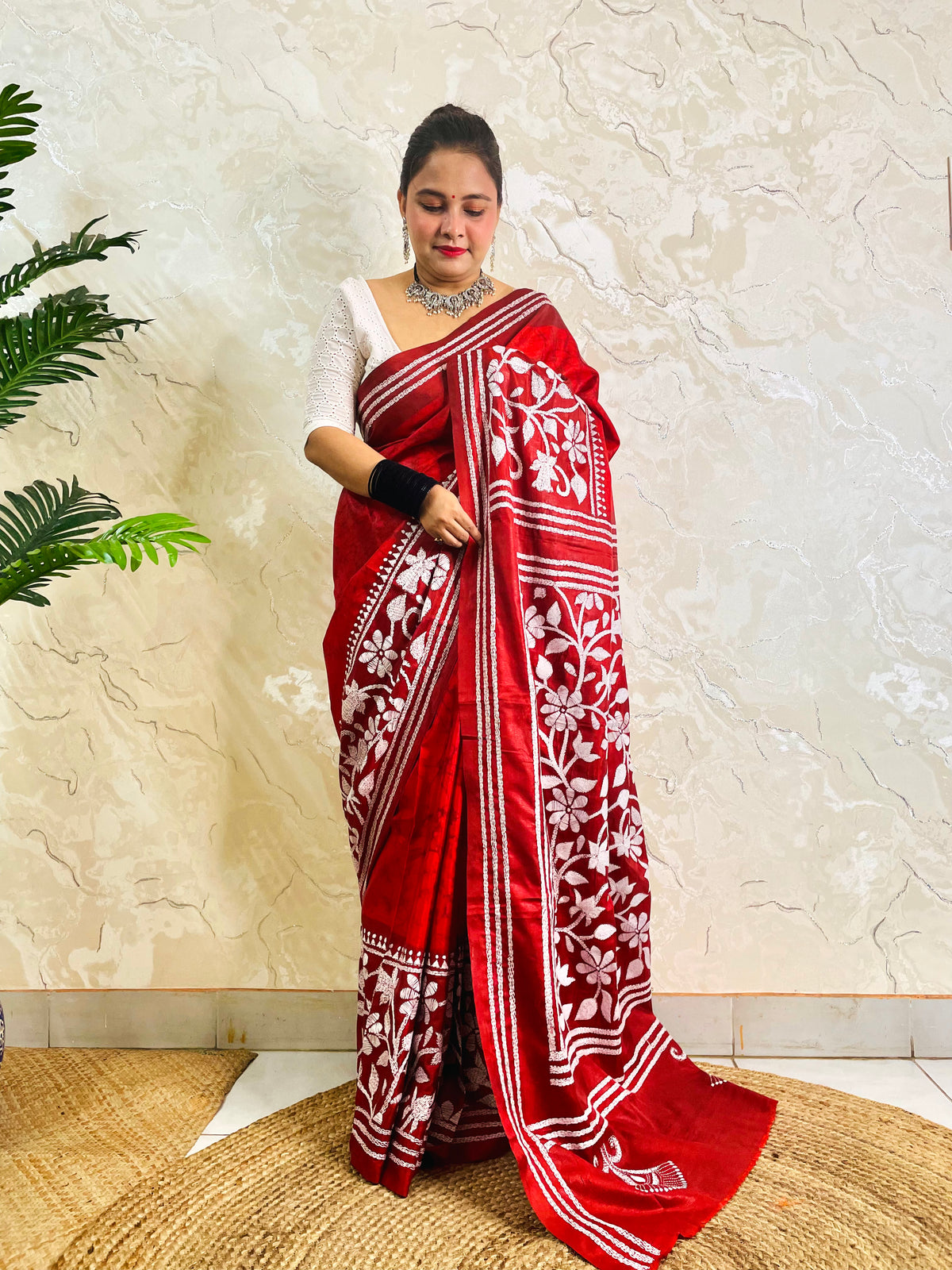Standing pose showing crimson batik Kantha saree hem with white flower and leaf band
