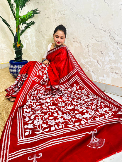 Seated pose in crimson red batik Kantha stitch saree with white flower and leaf pallu on Bangalore silk