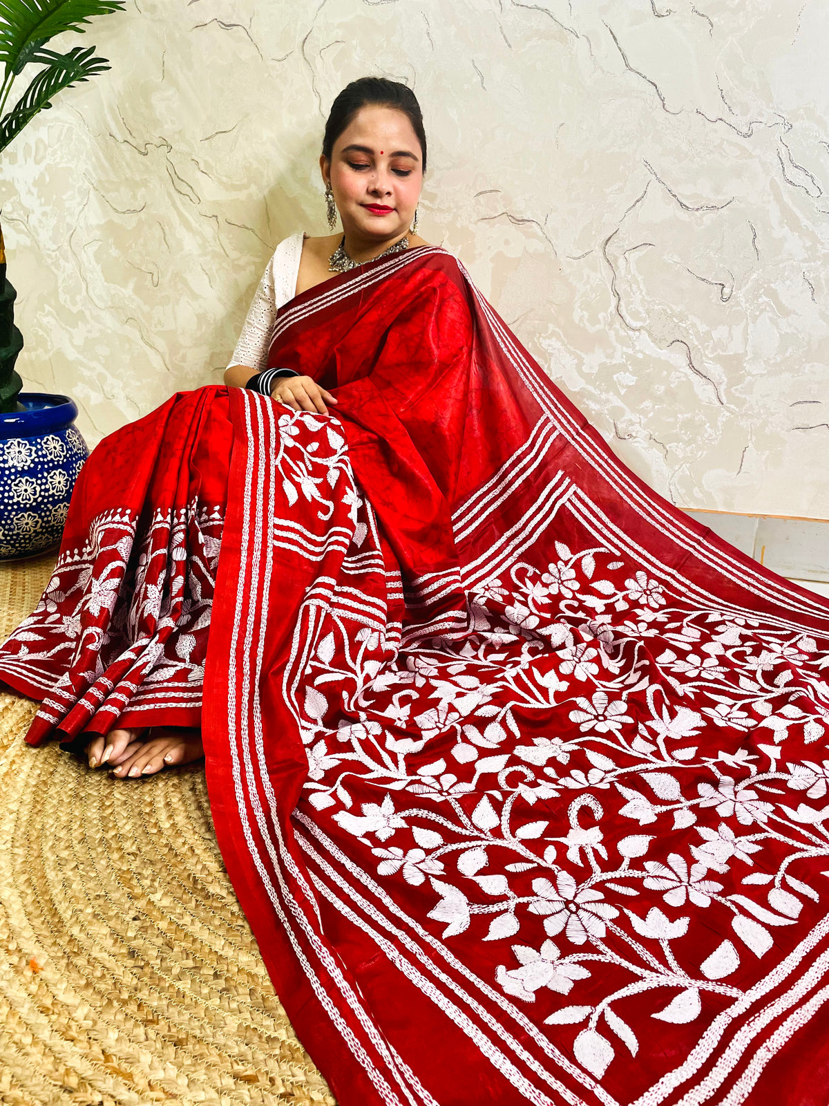 Side view of crimson red Kantha stitch saree pallu with framed flower garden and tassel motifs
