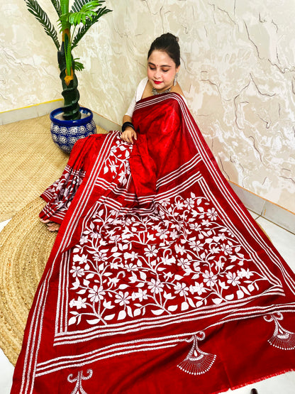 Top view of seated drape in crimson red batik saree with white Kantha floral panel and striped bands