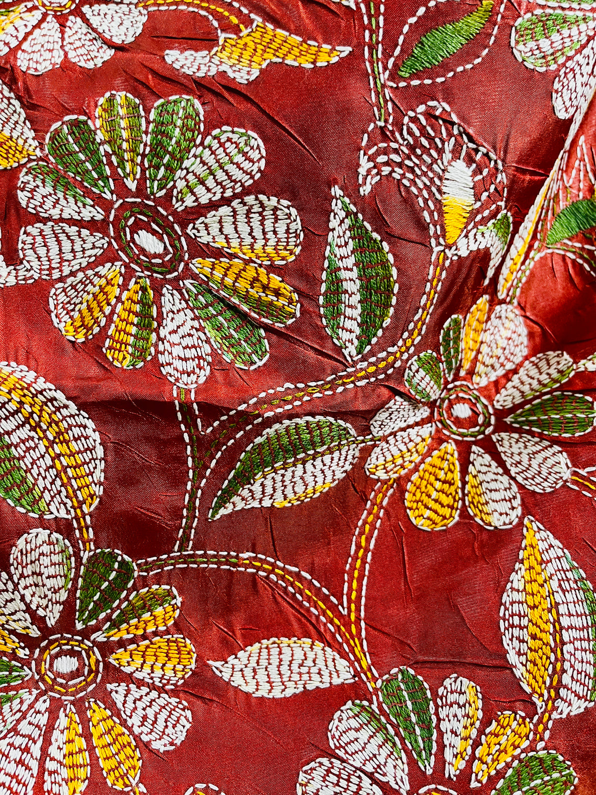 Close-up of rust red batik Kantha stitch silk with white, mustard and olive floral embroidery