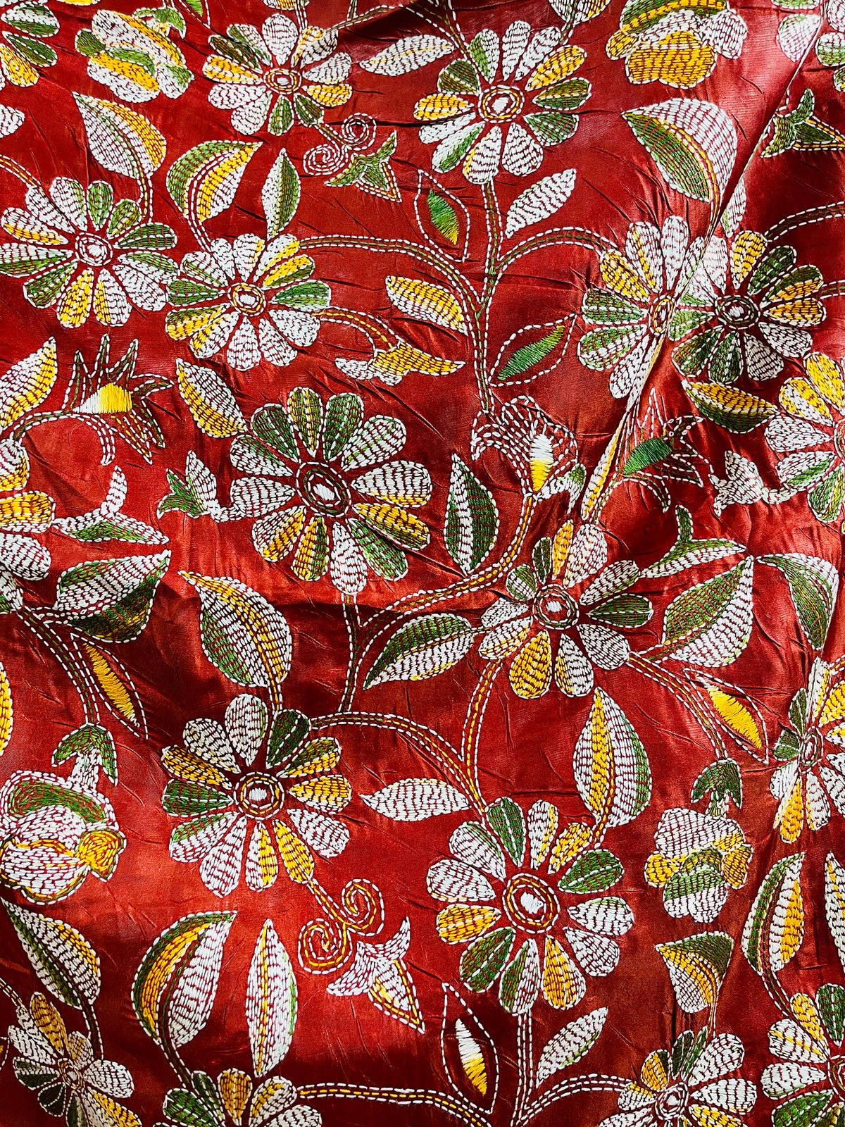 Close-up of rust red batik Kantha stitch silk with white, mustard and olive floral embroidery