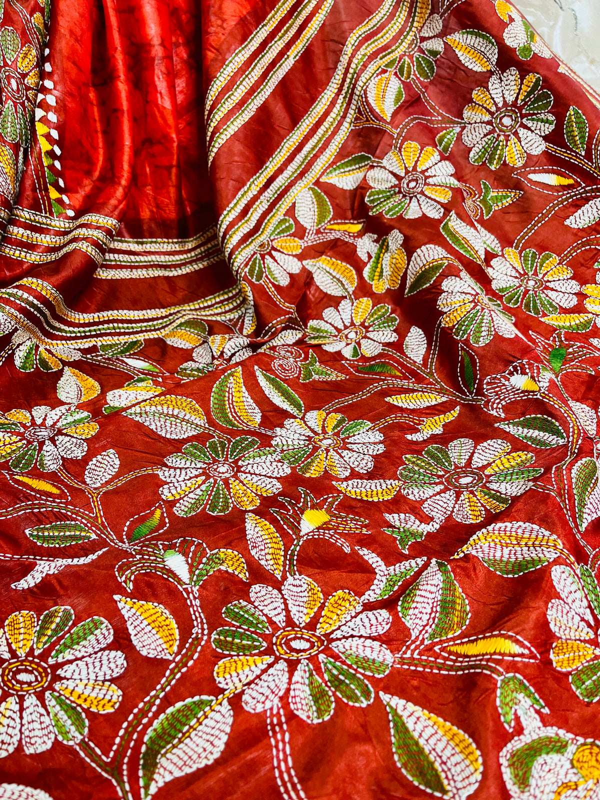 Close-up of rust red batik Kantha stitch silk with white, mustard and olive floral embroidery