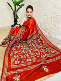 Seated pose in rust red batik Kantha saree with striped border and floral pallu