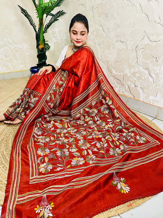 Seated pose in rust red batik Kantha saree with striped border and floral pallu