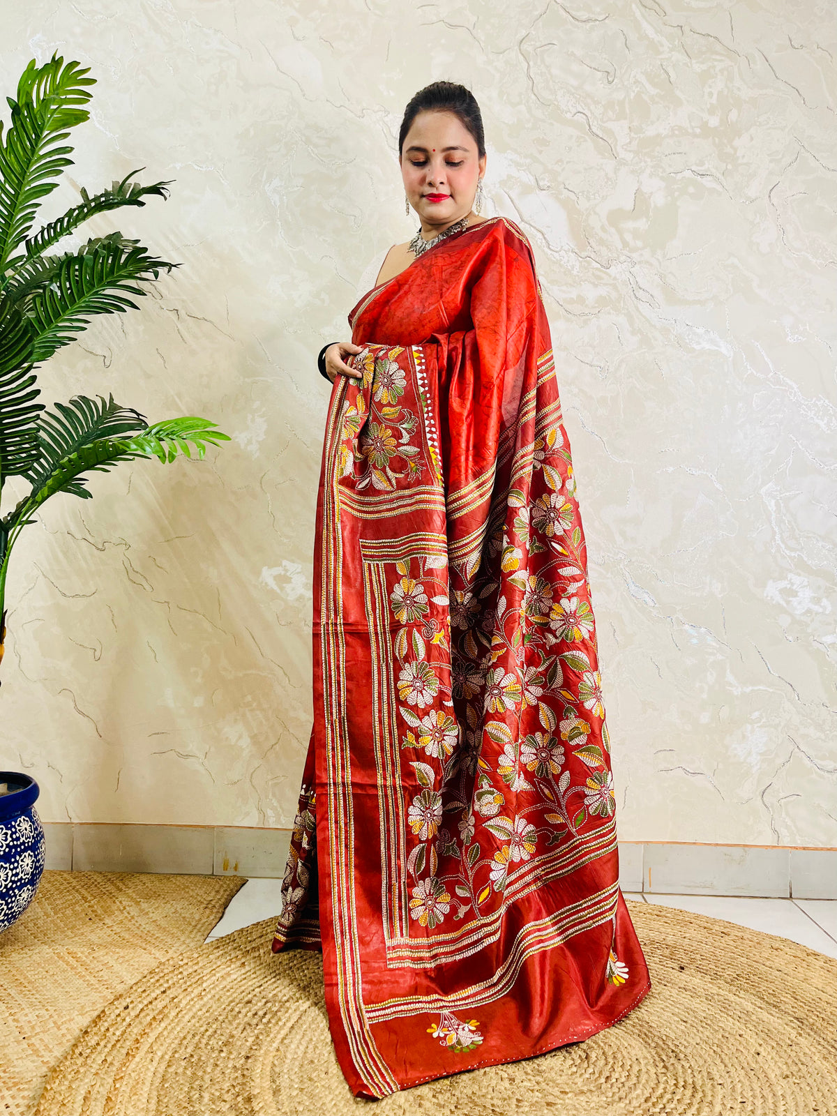 Side view of rust red Kantha stitch saree pallu with flower and leaf motifs