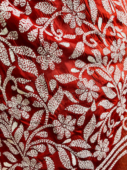 Close-up of crimson batik silk with white Kantha stitch floral embroidery