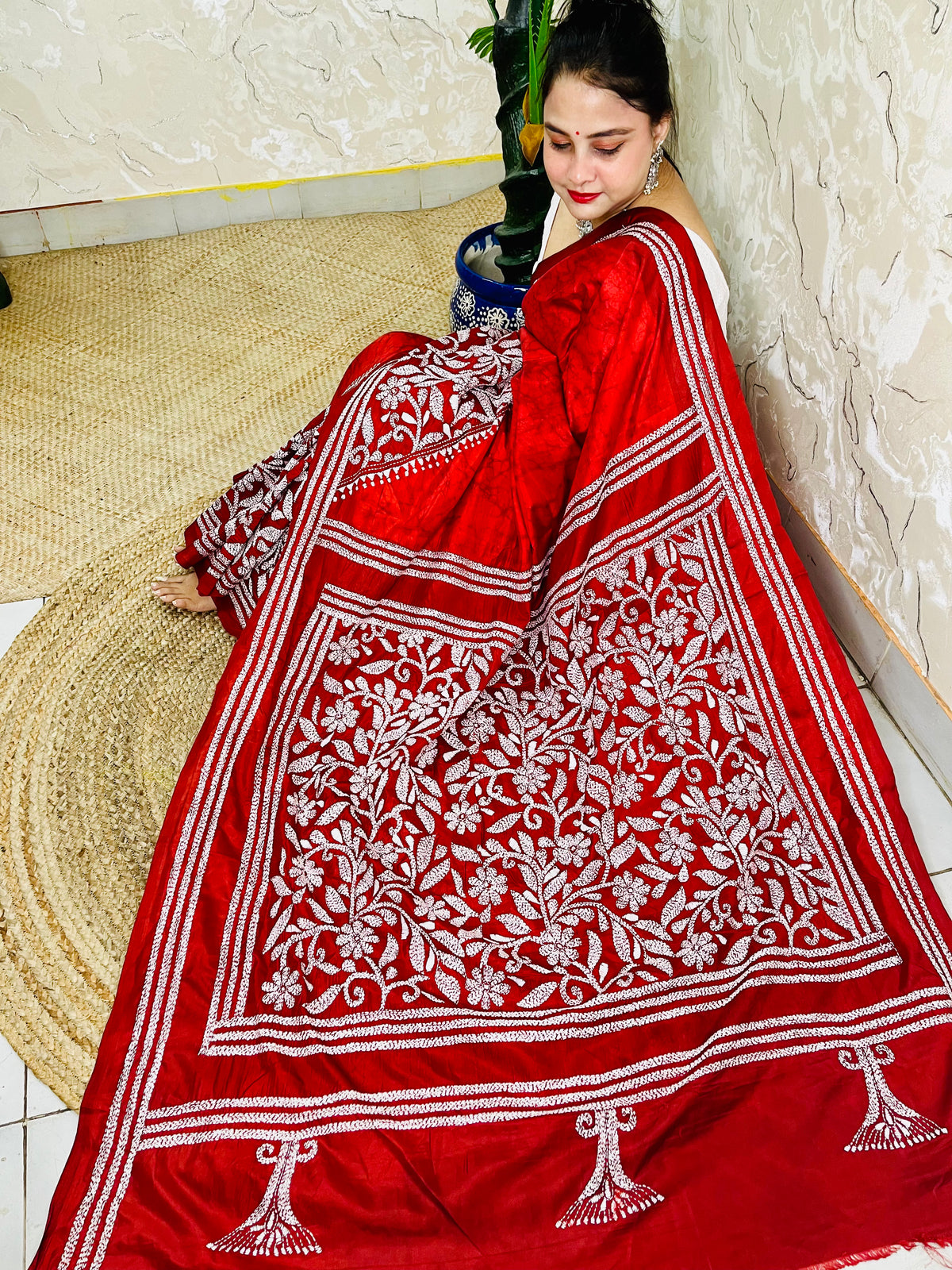 Seated pose in red batik Kantha saree with tree motif pallu on silk