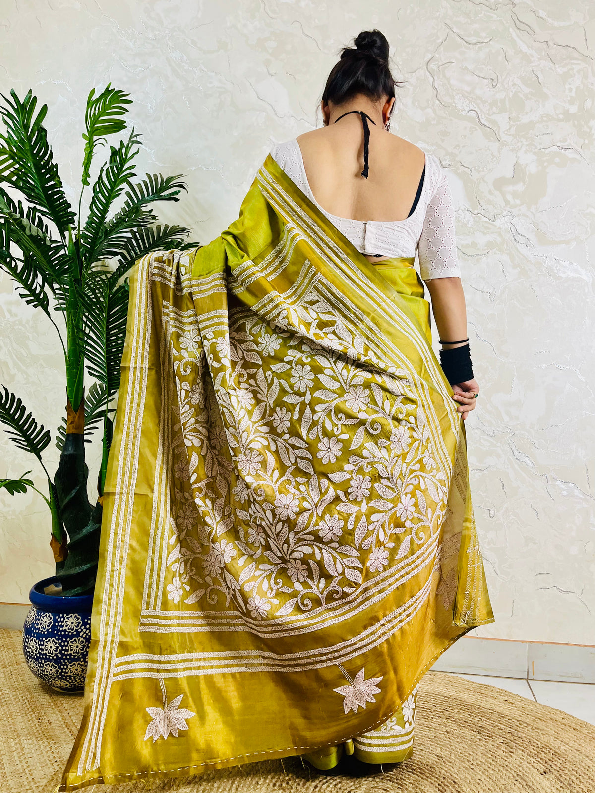 Back view of a woman modeling the exclusive handwoven olive green floral Katha stitch saree, highlighting the elaborate craftsmanship on the pallu