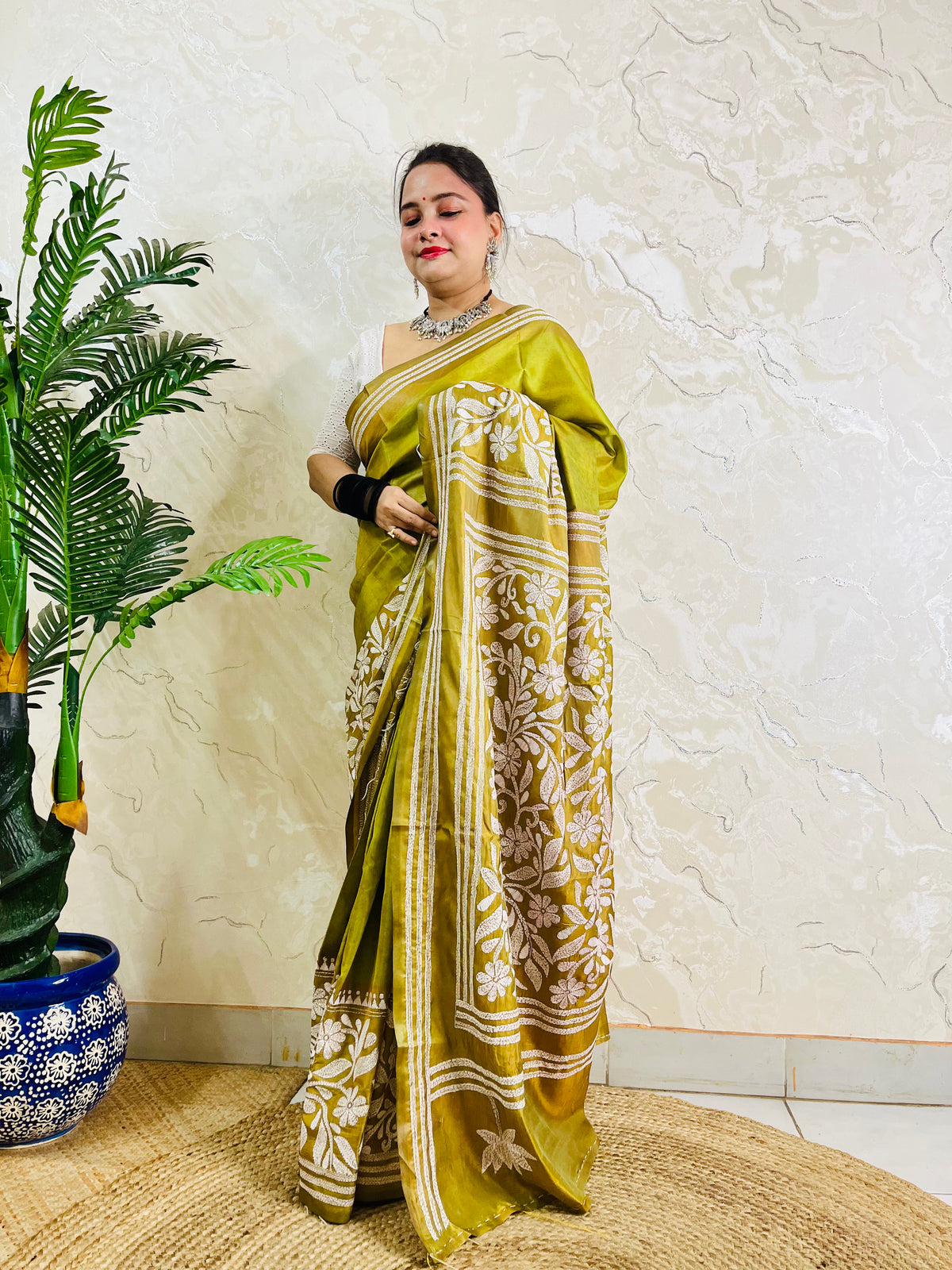 Full front view of a woman draped in the affordable luxury olive green Batik Katha silk saree showing the front pleats and pallu