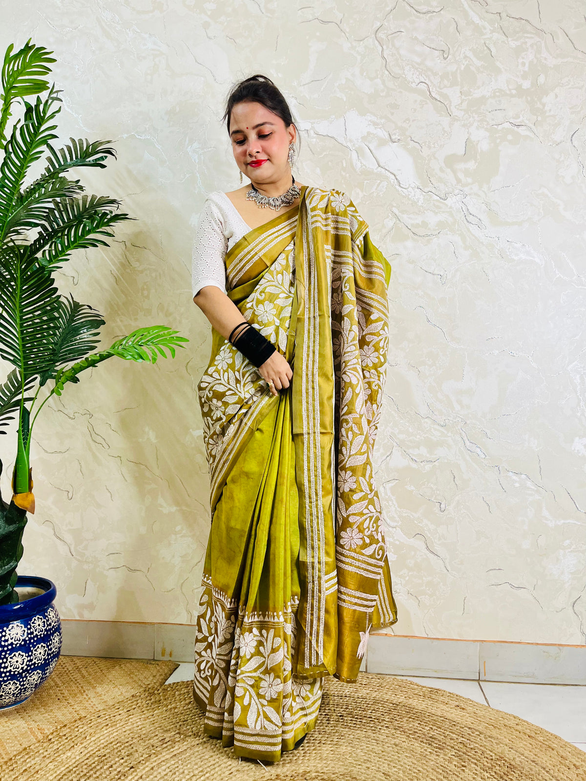 Full front view of a woman draped in the affordable luxury olive green Batik Katha silk saree showing the front pleats and pallu