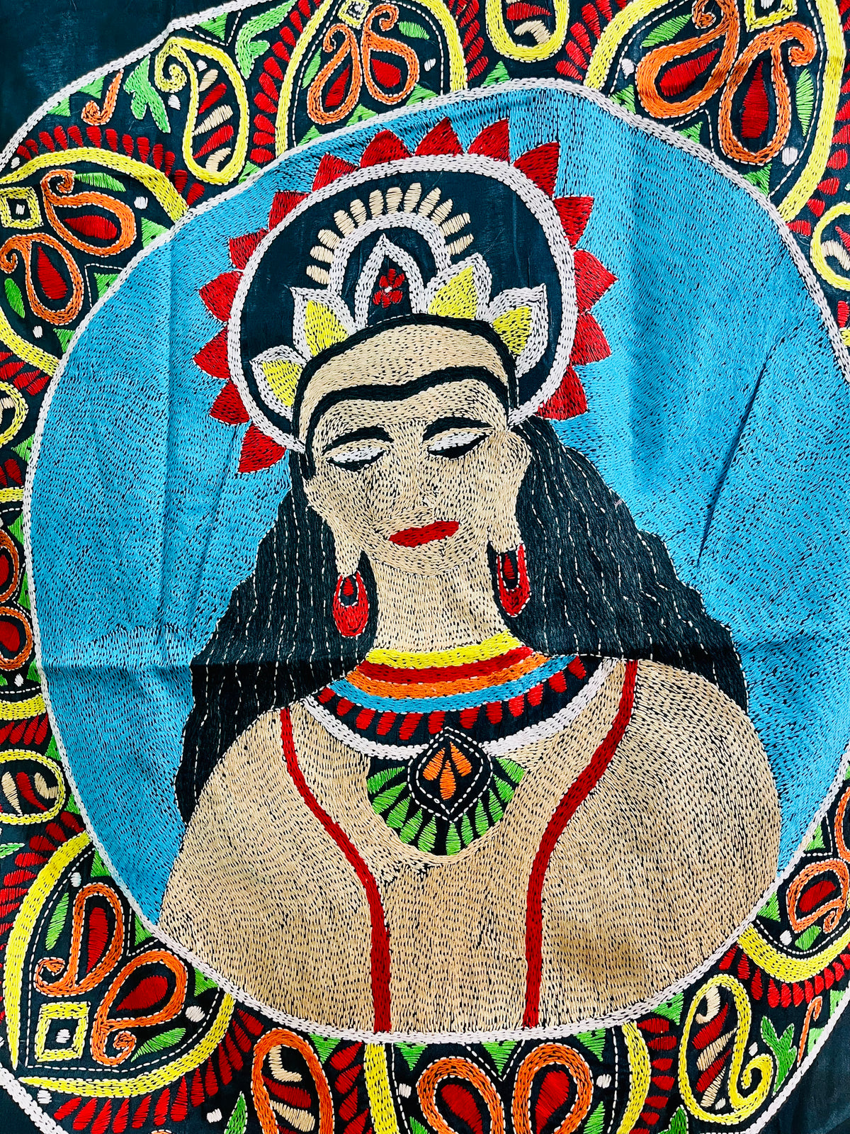 Close-up of Kantha stitch portrait with lotus-petal crown and paisley ring on black silk