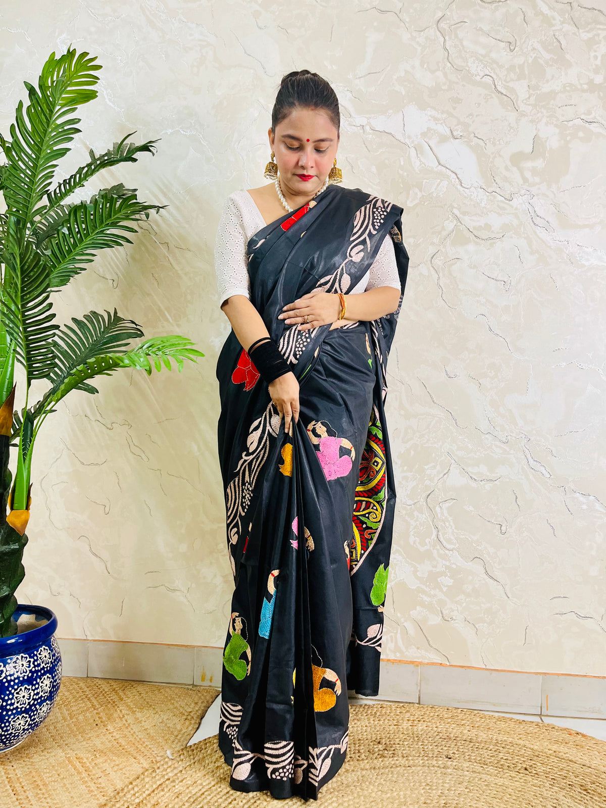 Pallu held open showing hand embroidered man's portrait in paisley mandala on black silk saree