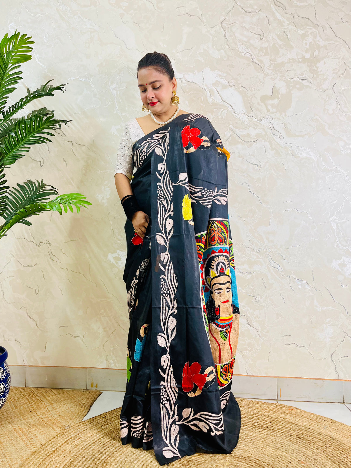 Pallu held open showing hand embroidered man's portrait in paisley mandala on black silk saree