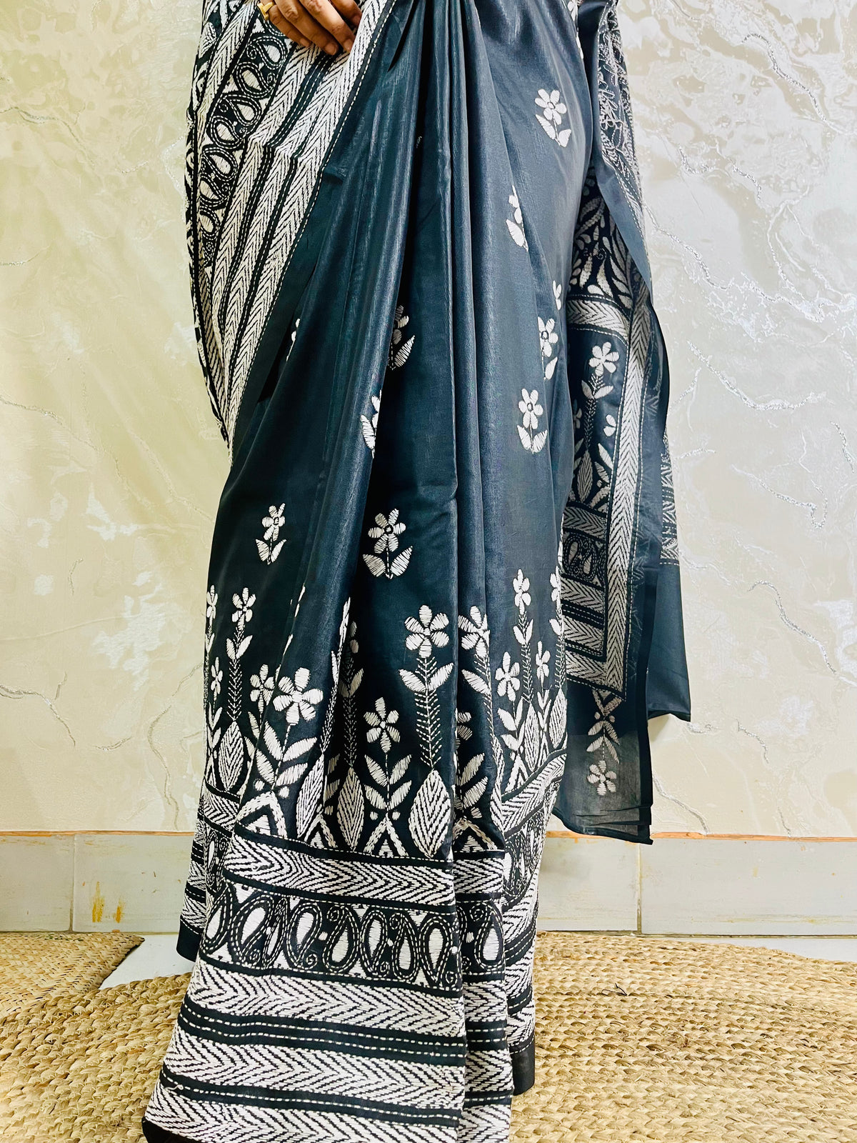 Close-up of white running thread Katha stitch embroidery detailing swirling paisley kalka and leaf motifs on black silk