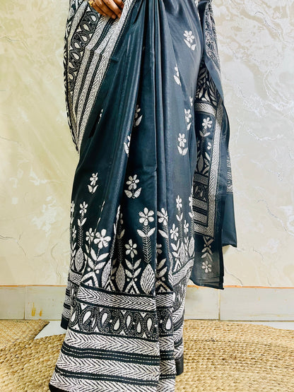 Close-up of white running thread Katha stitch embroidery detailing swirling paisley kalka and leaf motifs on black silk