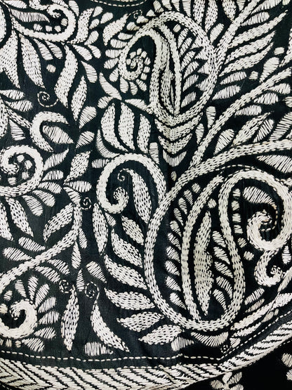 Close-up of white running thread Katha stitch embroidery detailing swirling paisley kalka and leaf motifs on black silk