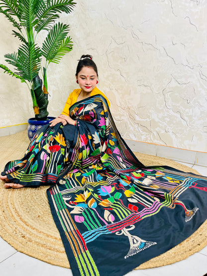 Woman seated in black multicolour Kantha stitch saree, front pallu spread view
