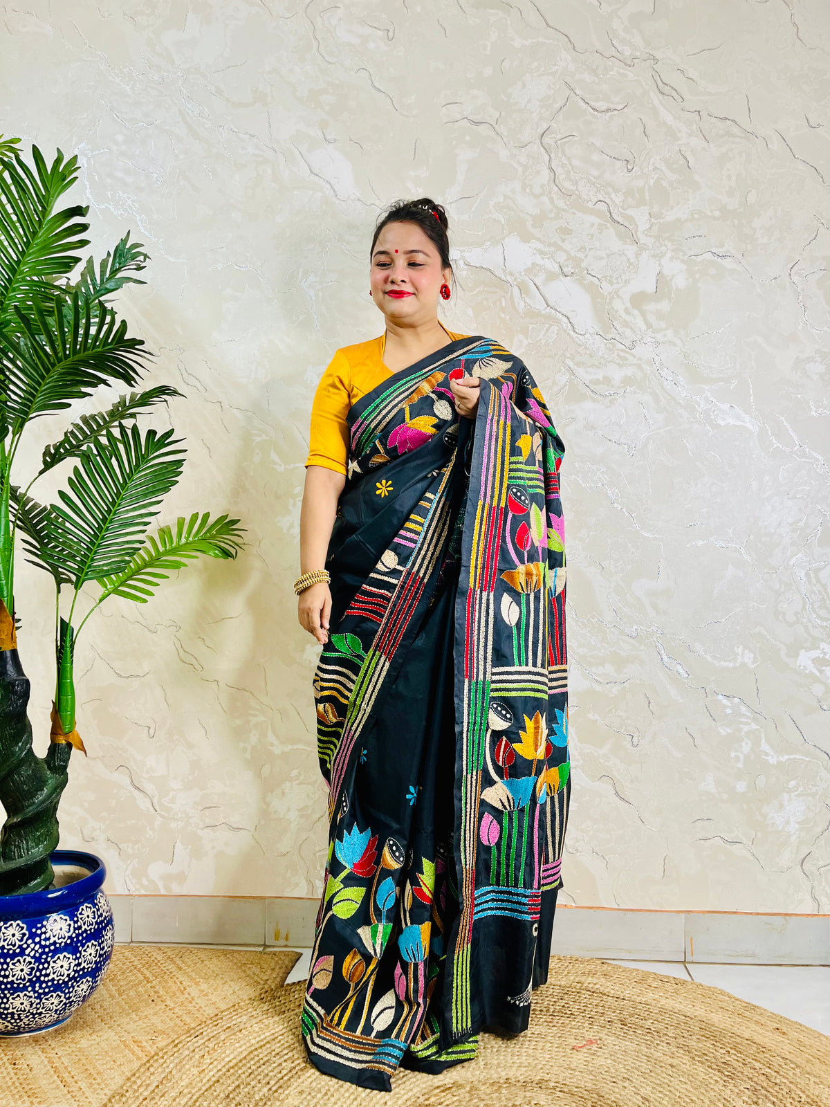 Woman standing in black Bangalore silk saree with rainbow lotus embroidery, back view