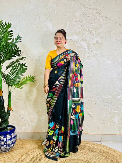 Woman standing in black Bangalore silk saree with rainbow lotus embroidery, back view