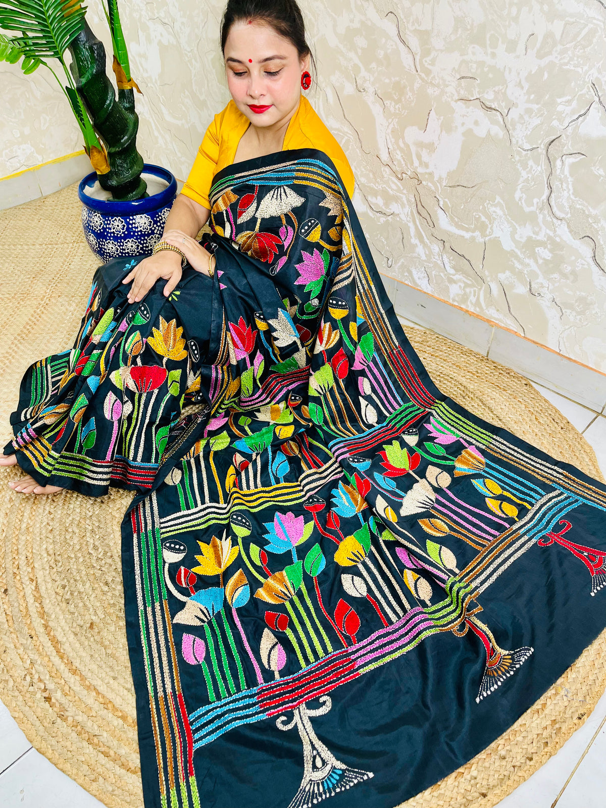 Woman seated in black Kantha lotus saree, side pallu draped view