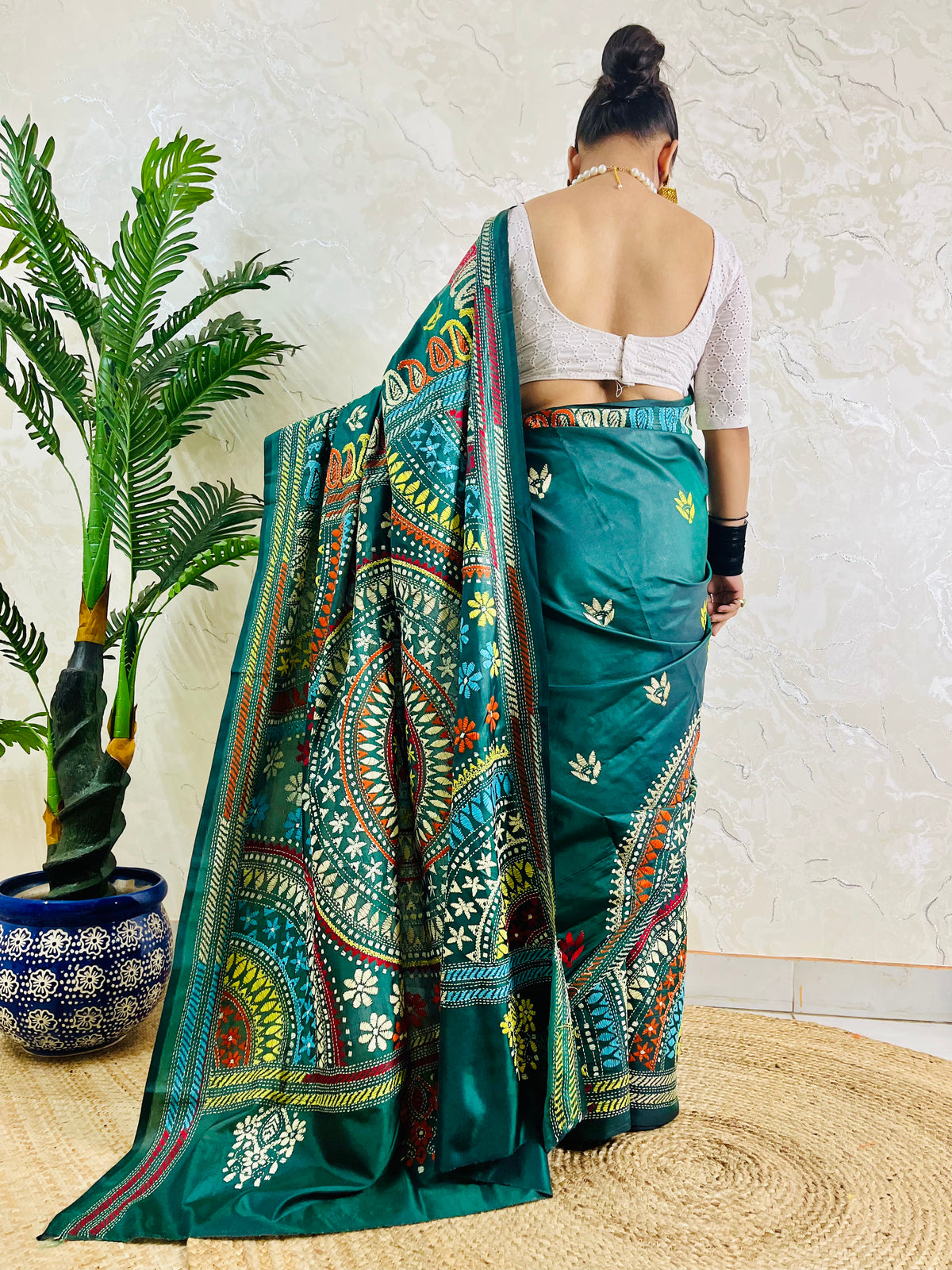 Rear view of a woman draped in the bottle green Kantha silk saree, showcasing the large circular multi-colored Mandala motif on the pallu.