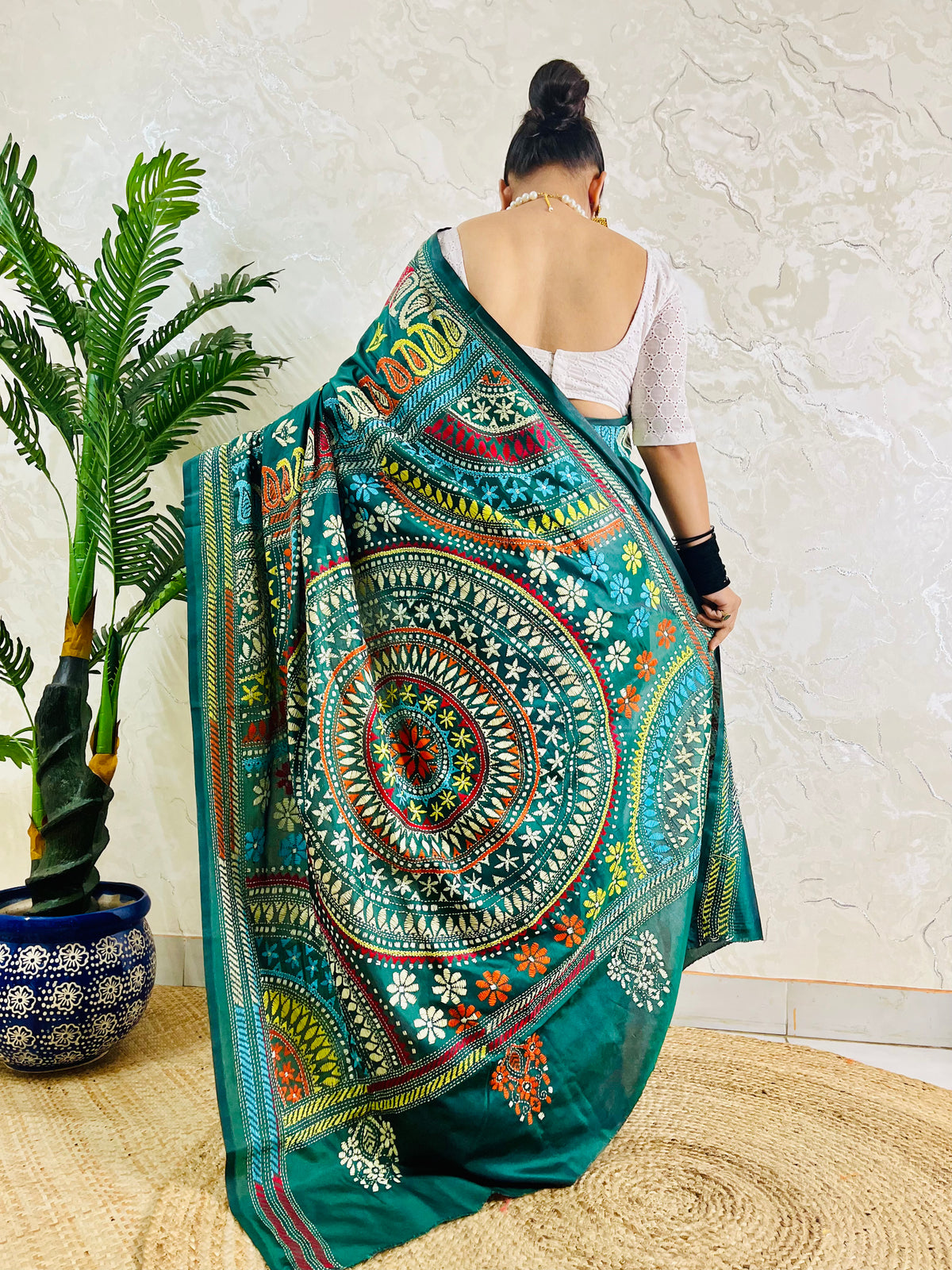 Rear view of a woman draped in the bottle green Kantha silk saree, showcasing the large circular multi-colored Mandala motif on the pallu.