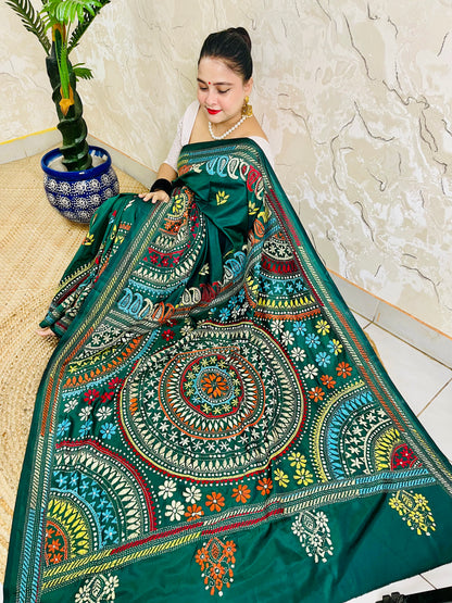 High-angle sitting pose displaying the spread-out hand-embroidered Mandala artwork and vibrant geometric thread work on deep bottle green silk.