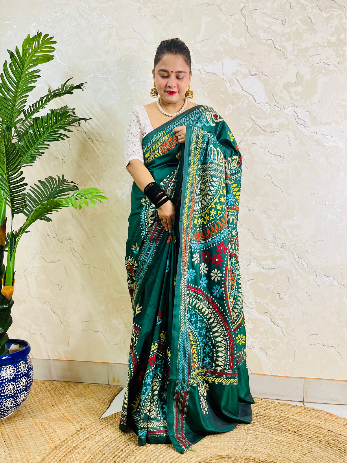 Model wearing the bottle green silk saree, showing the elegant drape of the embroidered pallu and subtle floral bootis on the pleats.