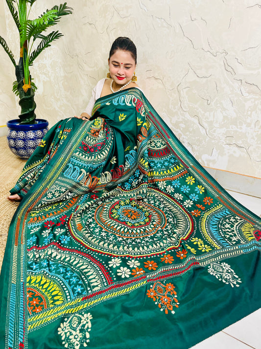 High-angle sitting pose displaying the spread-out hand-embroidered Mandala artwork and vibrant geometric thread work on deep bottle green silk.