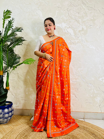 Front standing pose in bright orange saree with sky blue Kutch embroidery border