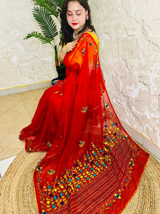 Handcrafted red organza silk saree with multicolour bullion stitch floral embroidery draped on model, side sitting view — Desi Aadat
