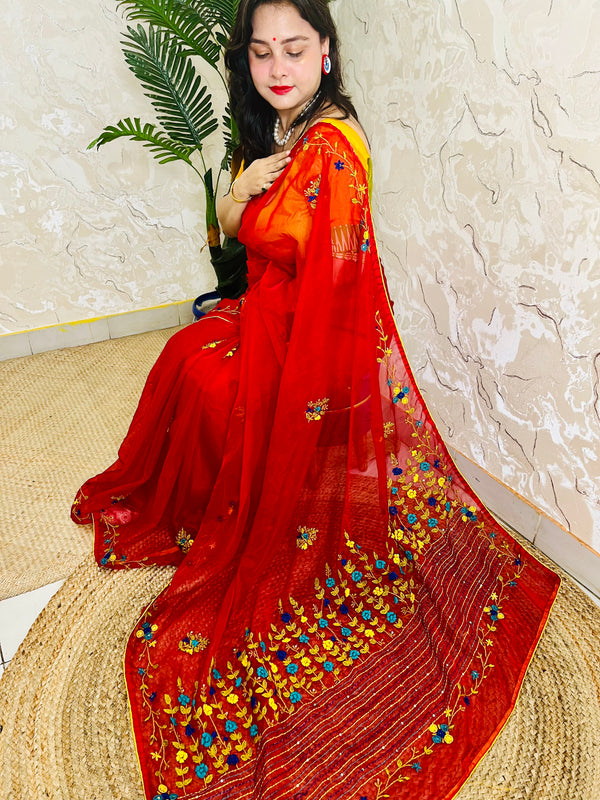 Handcrafted red organza silk saree with multicolour bullion stitch floral embroidery draped on model, side sitting view — Desi Aadat