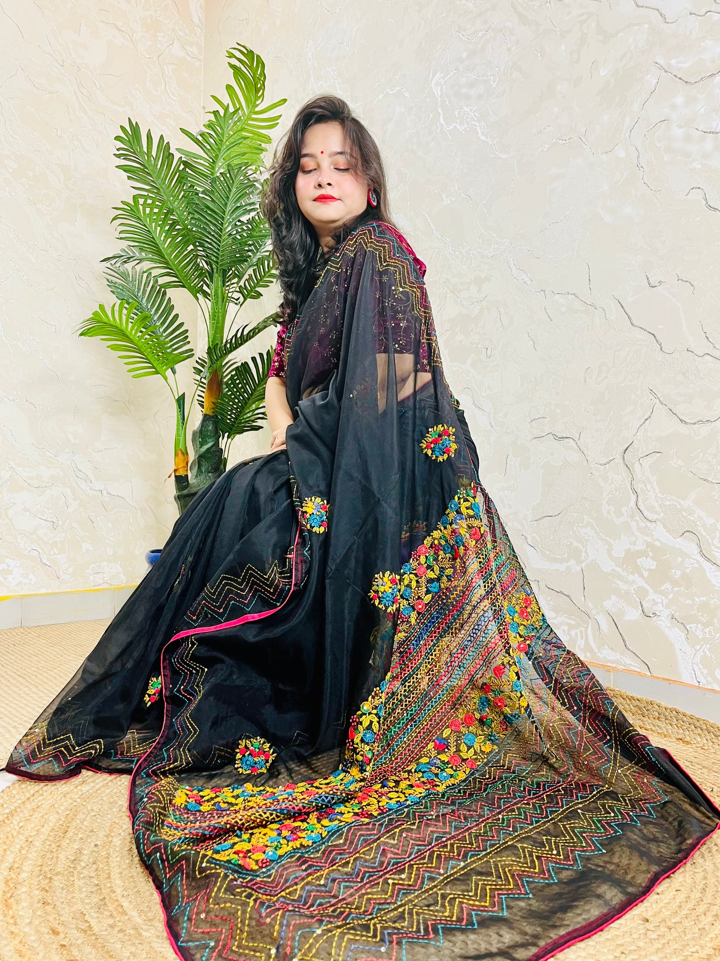 Woman sitting gracefully in handembroidered Black Organza Silk Saree with Bullion Stitch flowers and French knots — traditional saree look by Desi Aadat