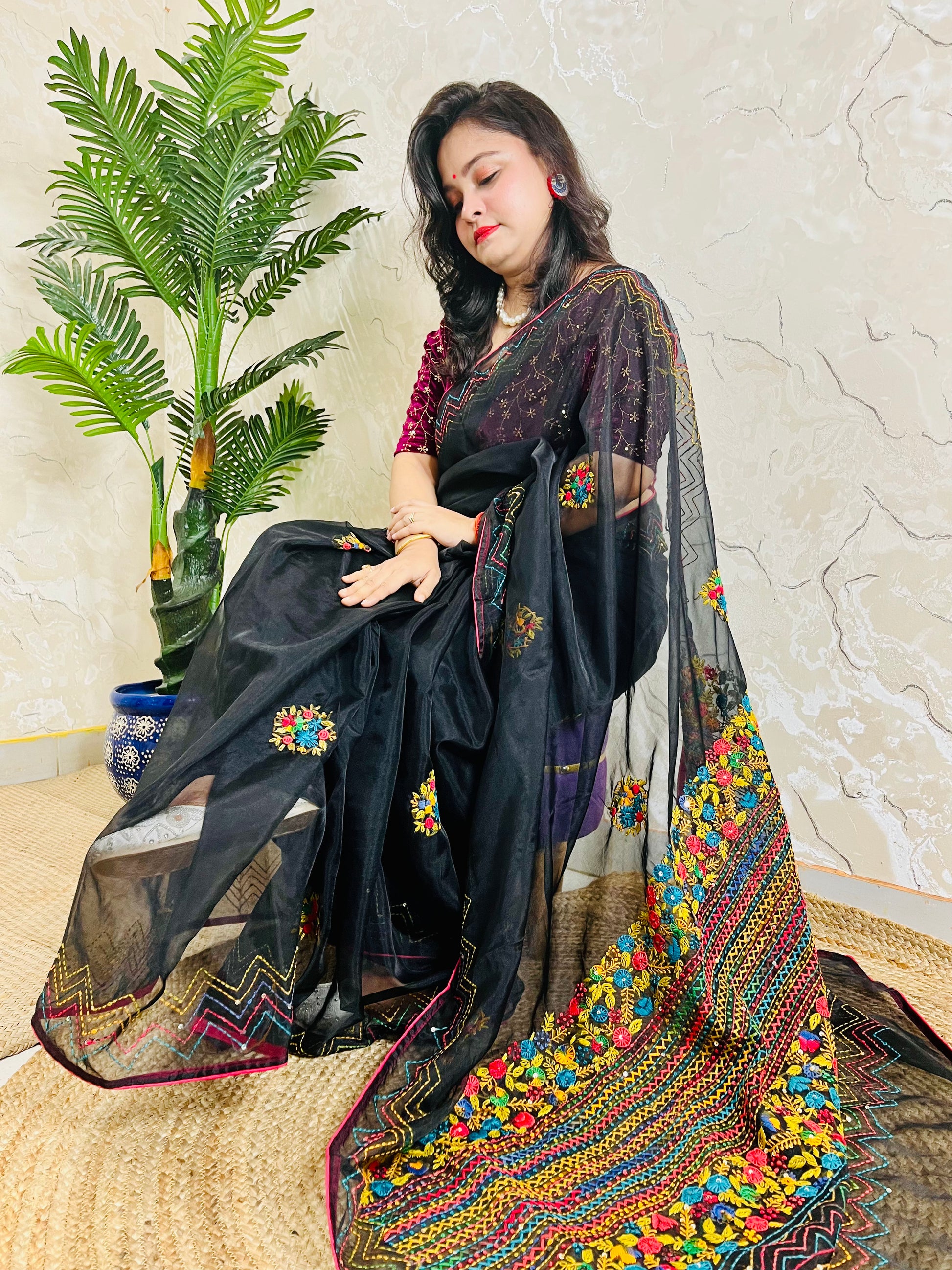 Woman sitting gracefully in handembroidered Black Organza Silk Saree with Bullion Stitch flowers and French knots — traditional saree look by Desi Aadat
