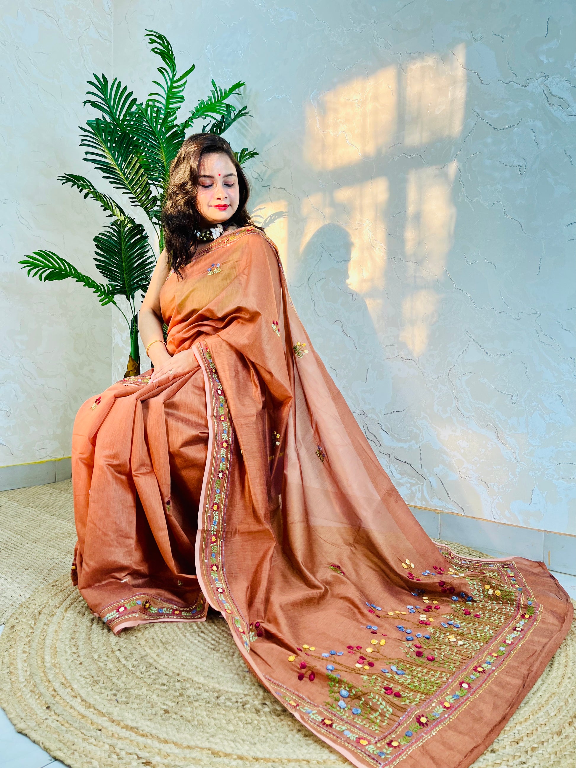 Woman seated in copper-brown handwoven Chanderi silk cotton saree with hand-stitched floral embroidery – Desi Aadat