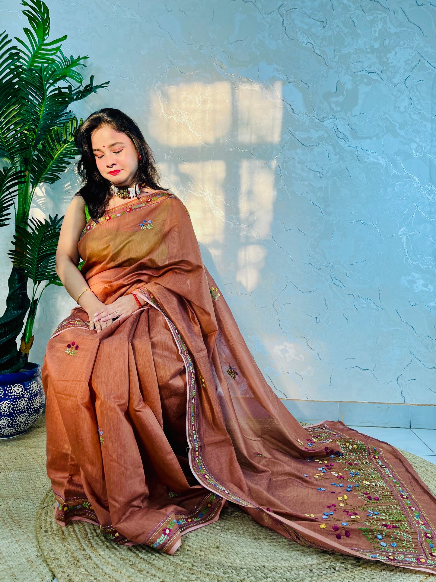 Woman seated in copper-brown handwoven Chanderi silk cotton saree with hand-stitched floral embroidery – Desi Aadat