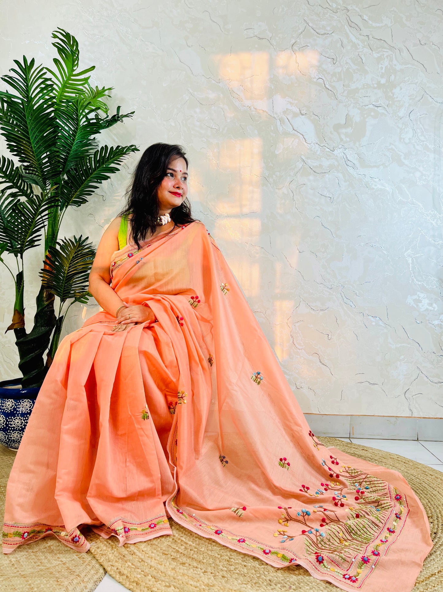 Woman seated in pastel peach Chanderi silk cotton saree with hand-embroidered Bullion Stitch and French Knot floral border – Desi Aadat