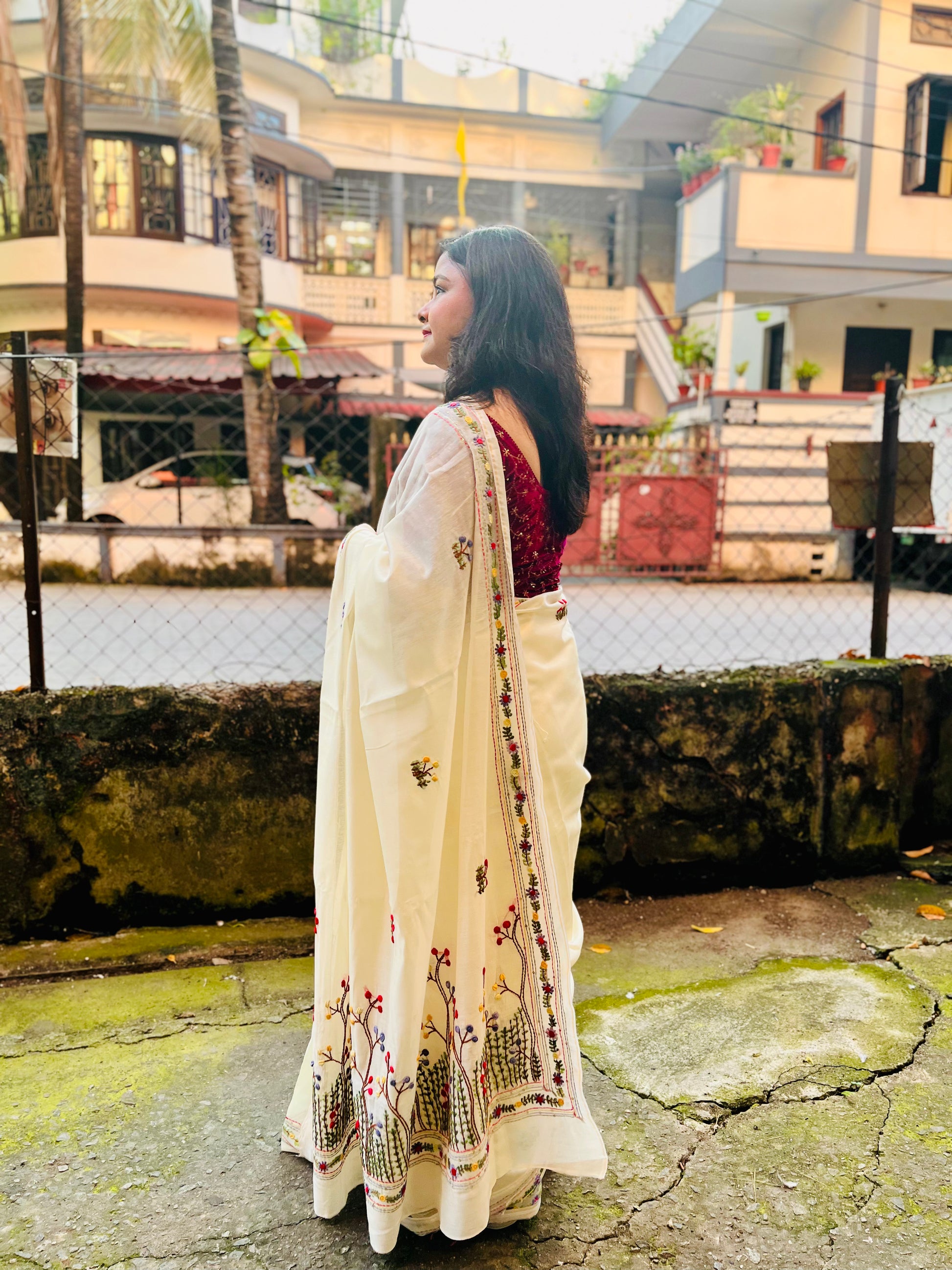 Back view of cream Chanderi silk cotton saree pallu showing dense Bullion Stitch and French Knot wildflower embroidery in flight — outdoor, Desi Aadat