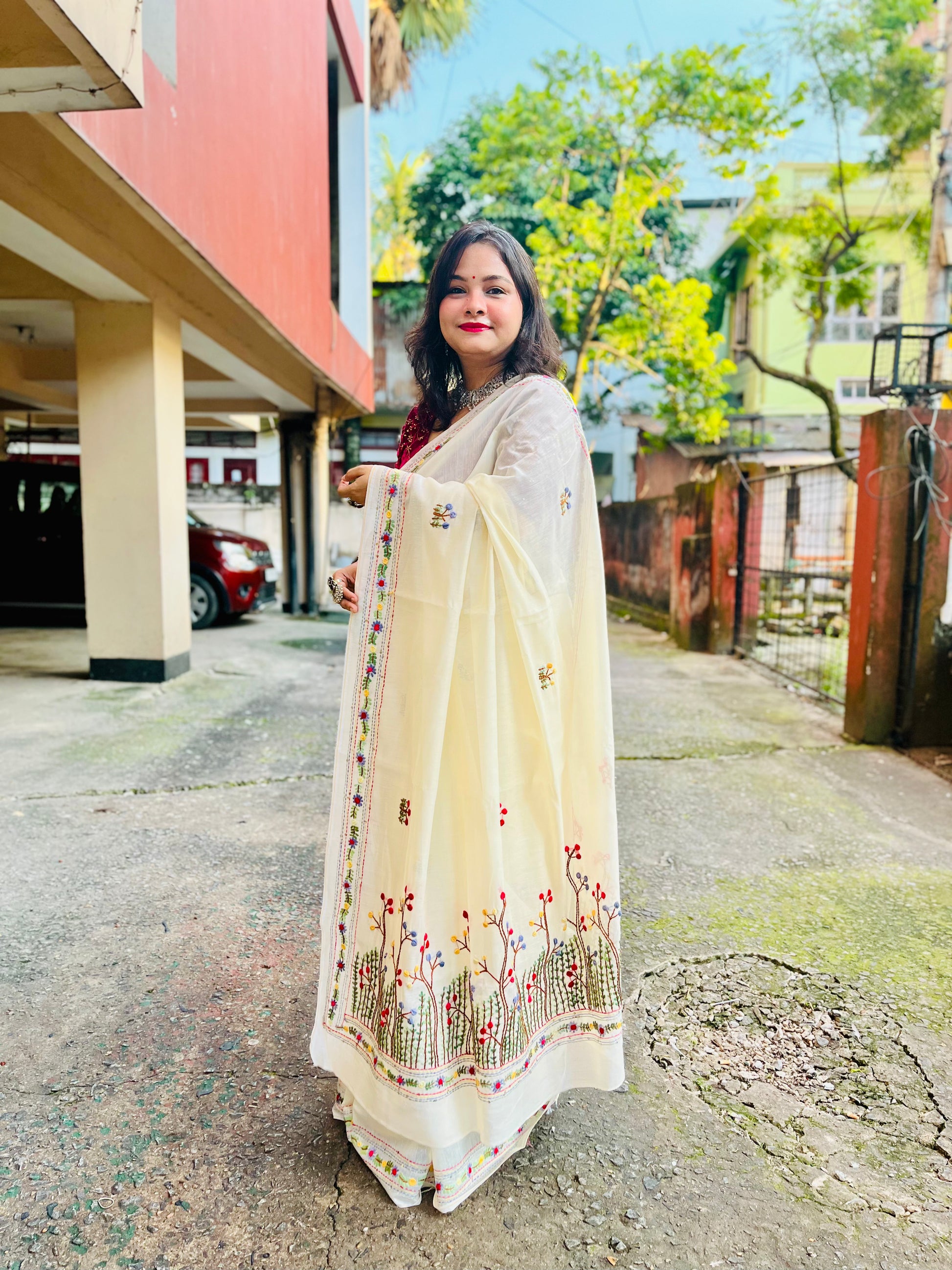 Back view of cream Chanderi silk cotton saree pallu showing dense Bullion Stitch and French Knot wildflower embroidery in flight — outdoor, Desi Aadat