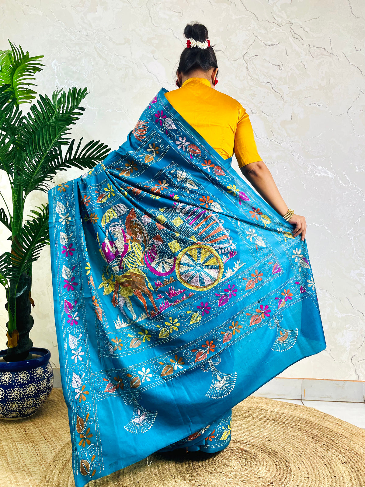 Back standing view of peacock blue Kantha stitch saree with floral border