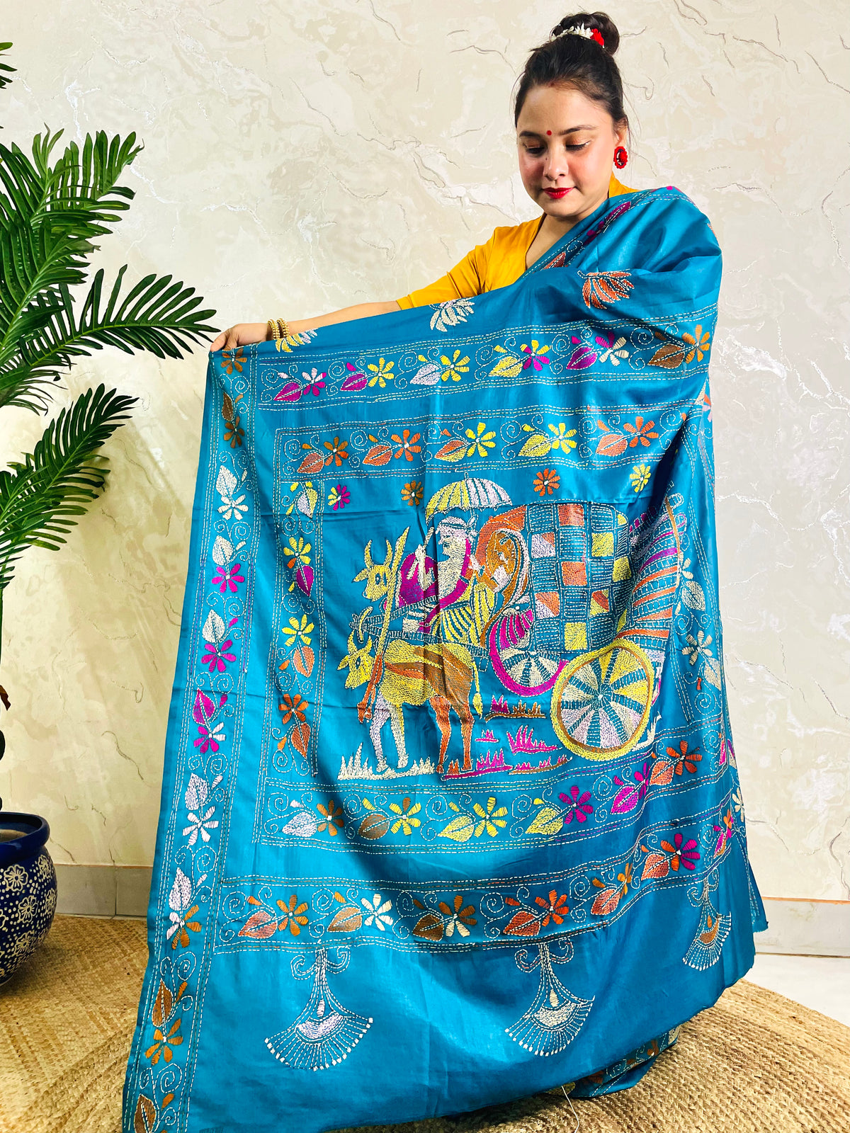 Back standing view of peacock blue Kantha stitch saree with floral border