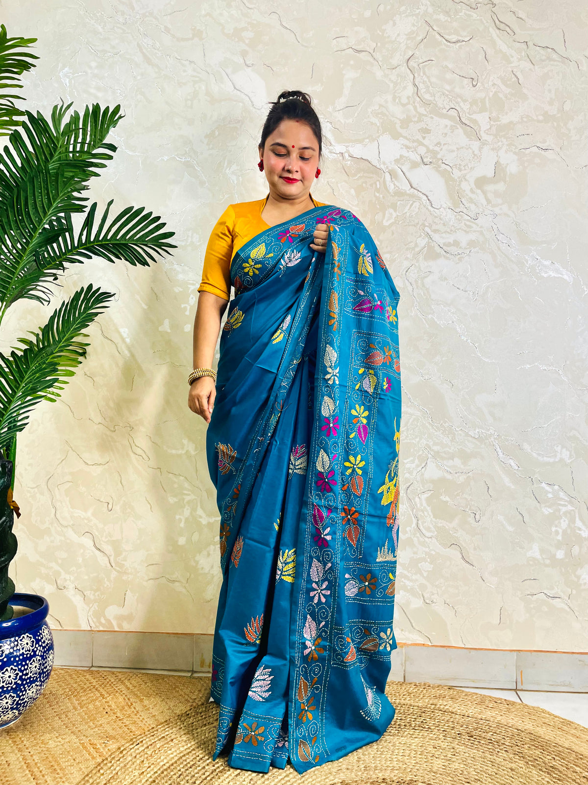 Woman standing in peacock blue Kantha saree with floral border, front view