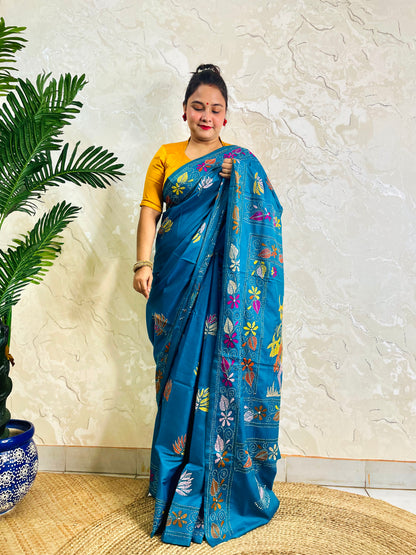 Woman standing in peacock blue Kantha saree with floral border, front view
